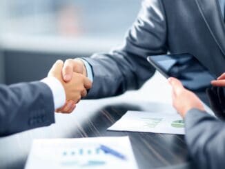 Business handshake over deal documents, illustrating a mergers and acquisitions guide for in-house counsel