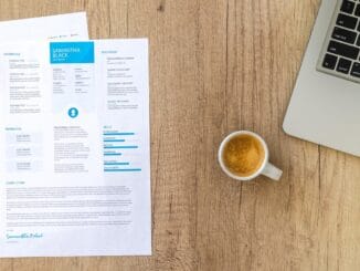 Printed resume on a desk beside a laptop and coffee, illustrating a LinkedIn profile versus a resume