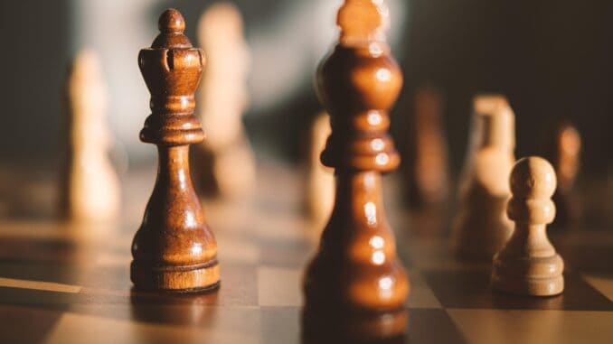 Two wooden chess kings on a board, a general counsel and board strategy concept