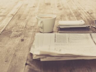 In-house counsel news briefing: a newspaper and a cup of coffee on a wooden table