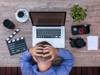 Overwhelmed lawyer with head in hands at a laptop, a lawyer wellbeing concern