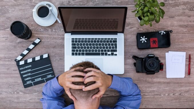 Lawyer wellbeing: overwhelmed lawyer at a laptop Overwhelmed lawyer with head in hands at a laptop, a lawyer wellbeing concern