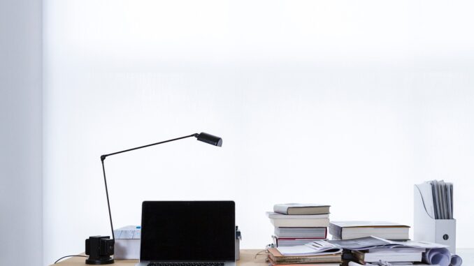 Laptop and paperwork on a desk as outside counsel work moves in-house